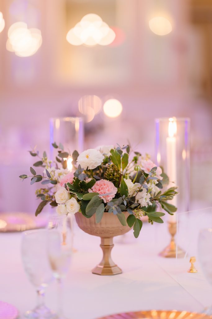 Gold urn with pink flowers in it.
